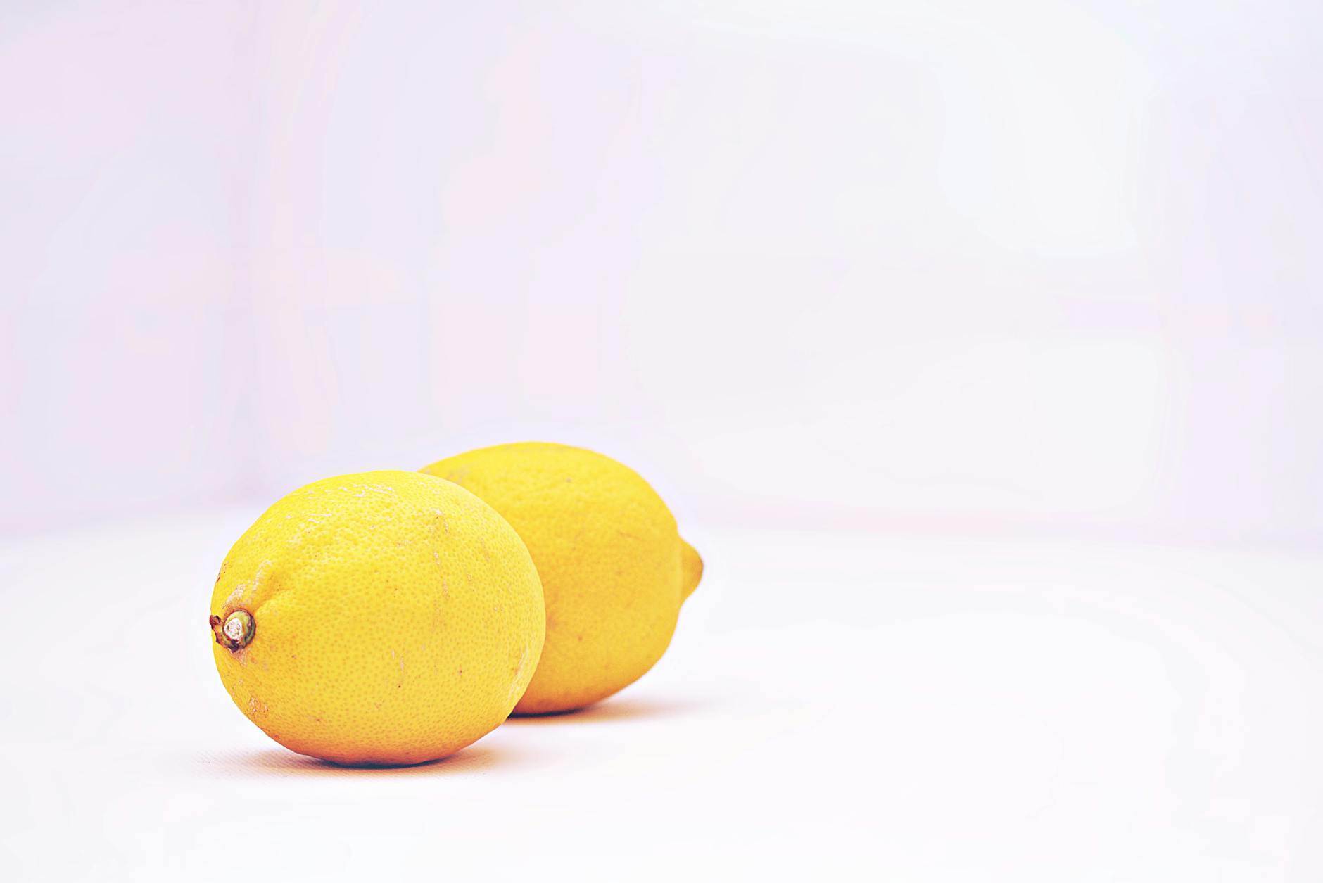 Two vibrant fresh lemons against a white background, symbolizing healing and renewal