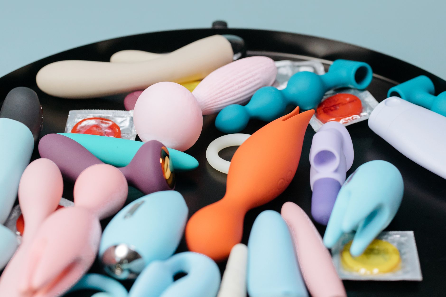 Two hands holding pink and blue vibrators, representing partnership and communication around pleasure