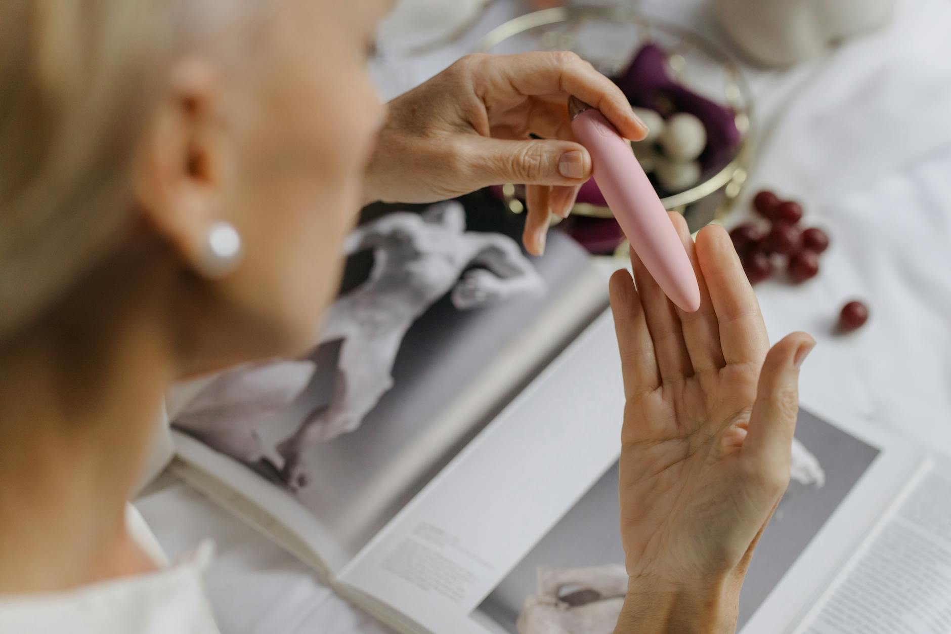Close-up of a hand holding a pink vibrator against a soft background, emphasizing intimate pleasure and self-care