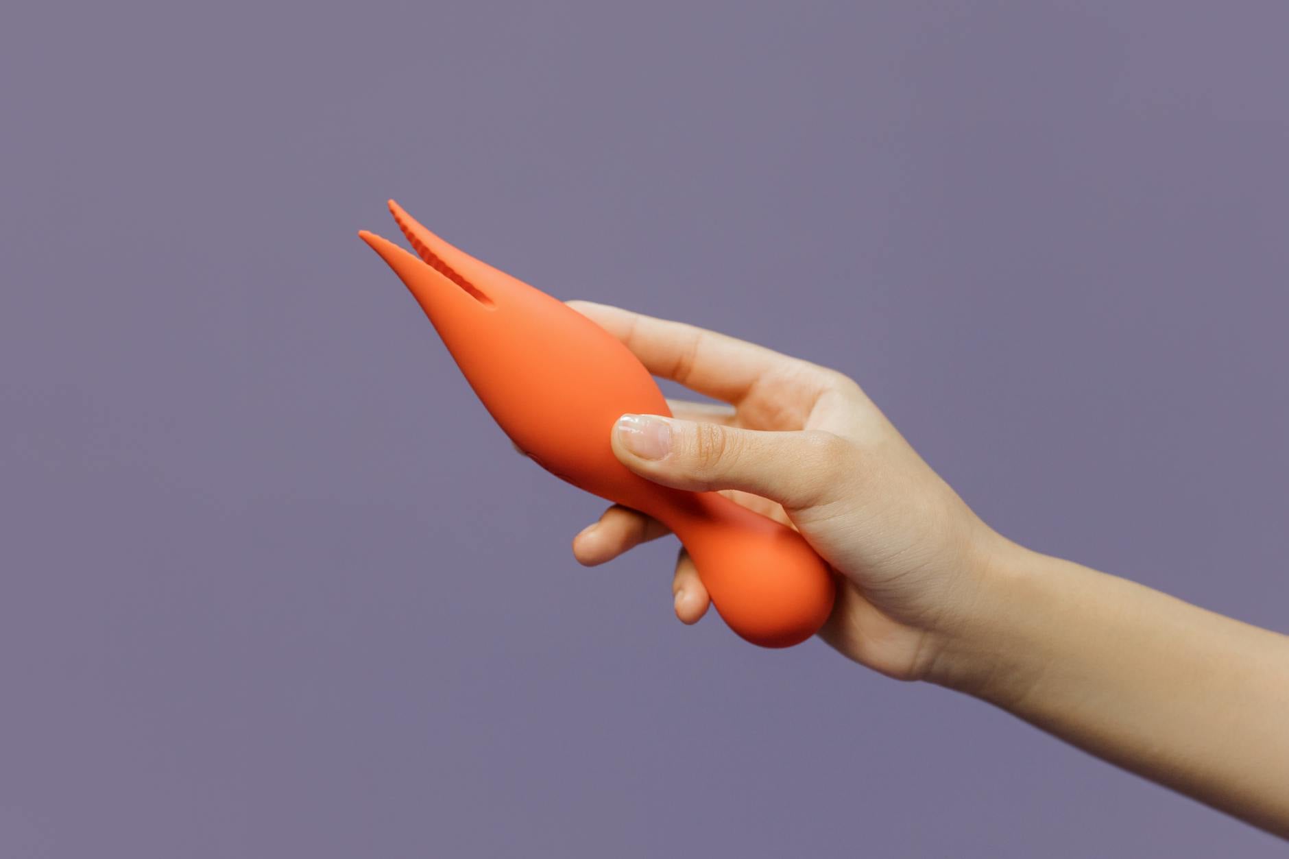 Hand holding a lemon clitoral vibrator against a purple backdrop, symbolizing the return of sexual pleasure and self-discovery.