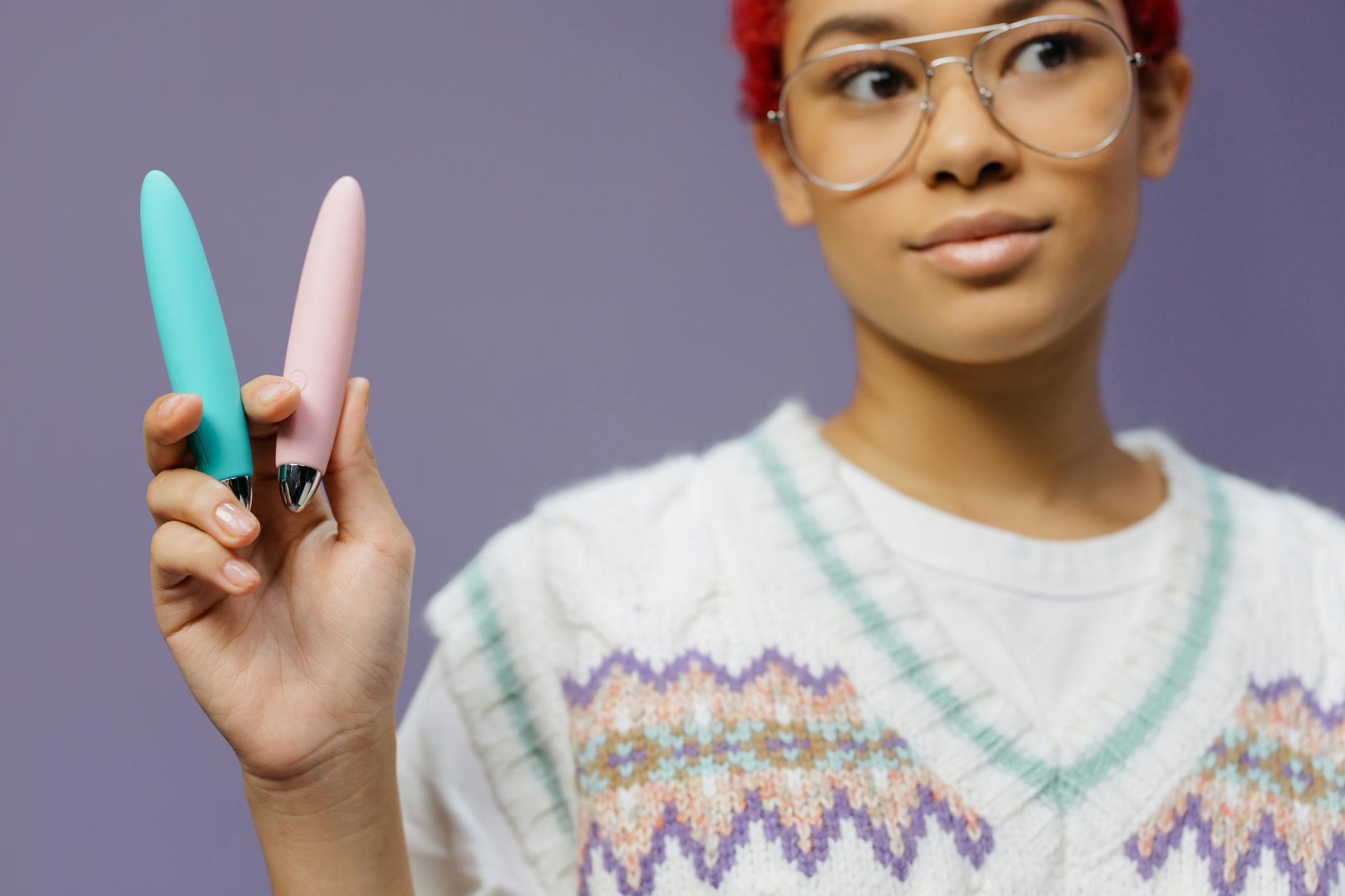 A blue silicone vibrator held in hand against a purple background, symbolizing gentle clitoral pleasure